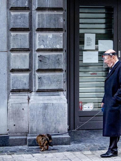 Ein alter Mann geht während des Lockdowns mit seinem Hund in Lüttich spazieren.