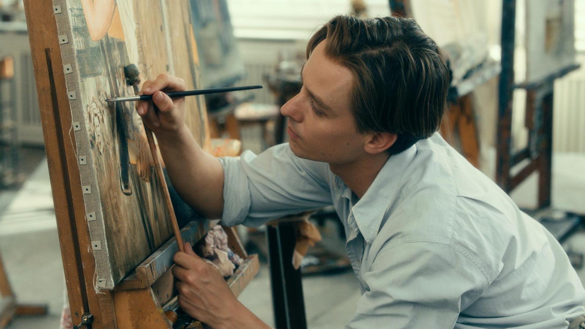 Tom Schilling vor einer Leinwand mit einem Pinsel in der Hand. Szene aus dem Film "Werk ohne Autor".
