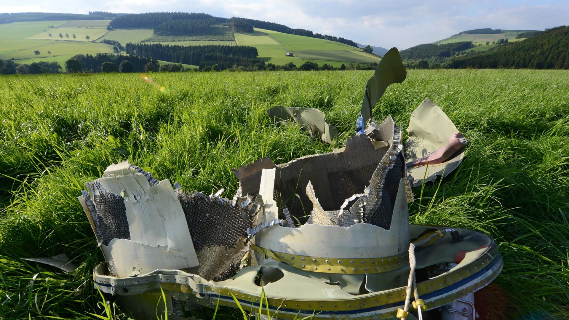 Ein Trümmer-Teil von dem Flugzeug liegt auf einer Wiese. Ein Trümmer-Teil von dem Flugzeug liegt auf einer Wiese.