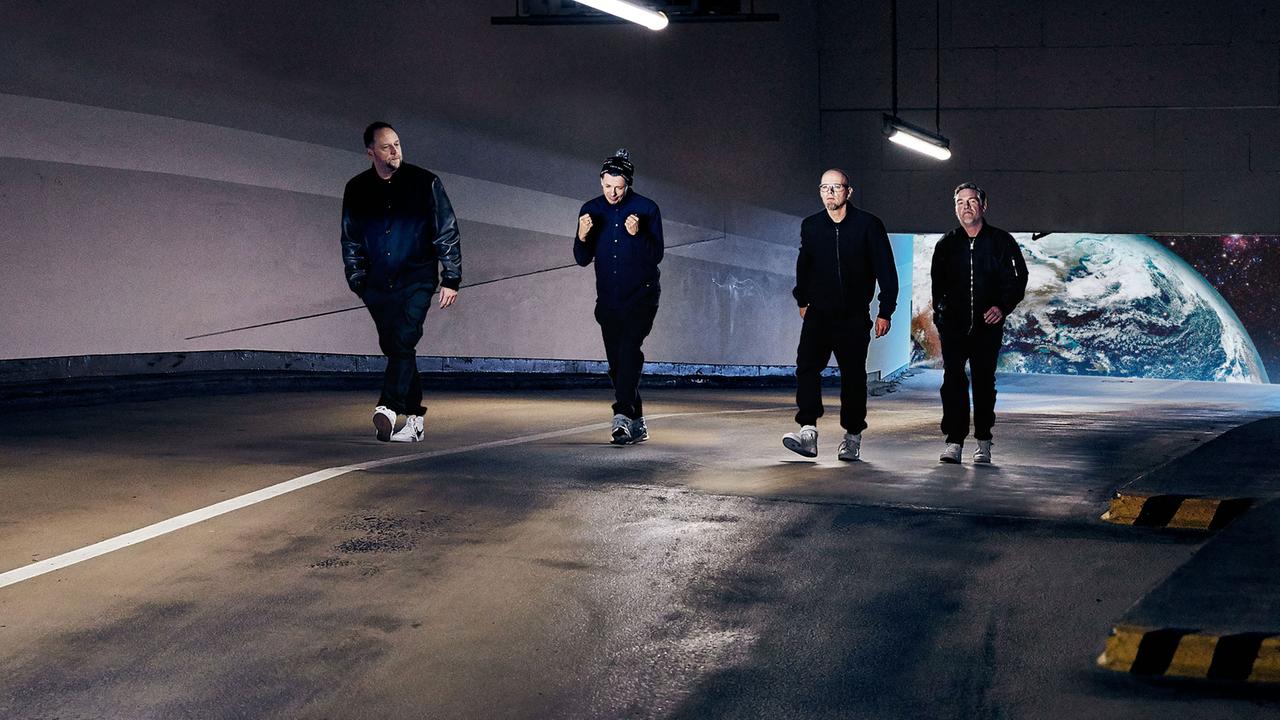 Die Stuttgarter Band Die Fantastischen Vier in einem Tunnel, im Hintergrund, durch ein Tunnelende gesehen, scheint die Erde zu sein.