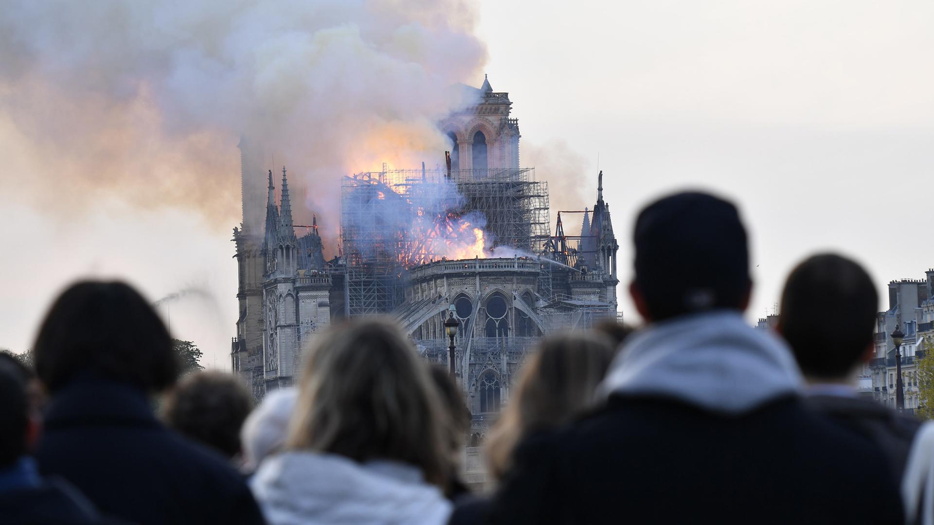 Passanten blicken auf die brennende Notre-Dame-Kathedrale
