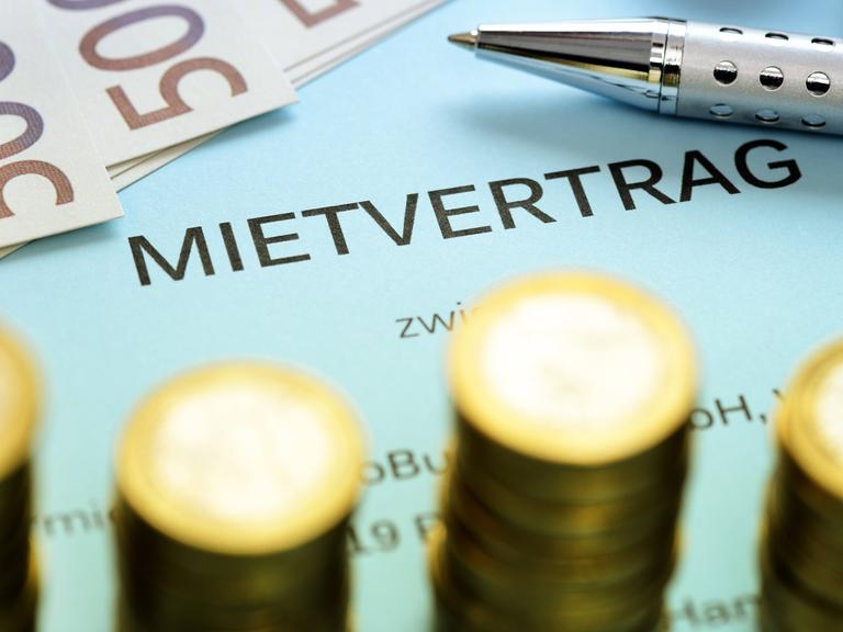 Mehrere Euromünzen und 500-Euro-Scheine liegen auf einem Mietvertrag.