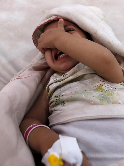 Ein Mädchen liegt im Jemen in einem Krankenhausbett und weint.