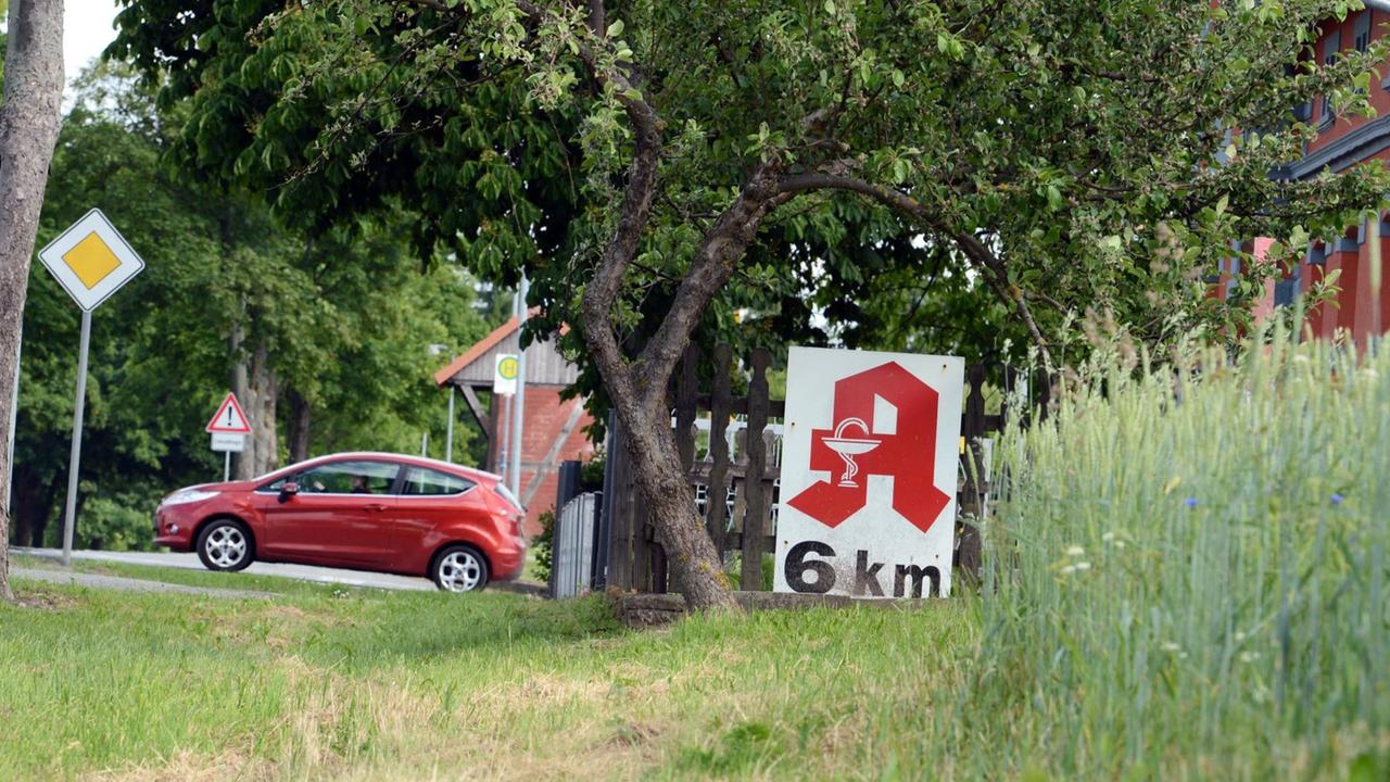 Ein Schild weist am 11.06.2013 bei Stavenhagen (Mecklenburg-Vorpommern) an einem Gartenzaum unter einem Apfelbaum an einer Straße auf eine Apotheke hin, die sich in sechs Kilometern Entfernung befindet. Foto: Jens Kalaene/dpa | Verwendung weltweit