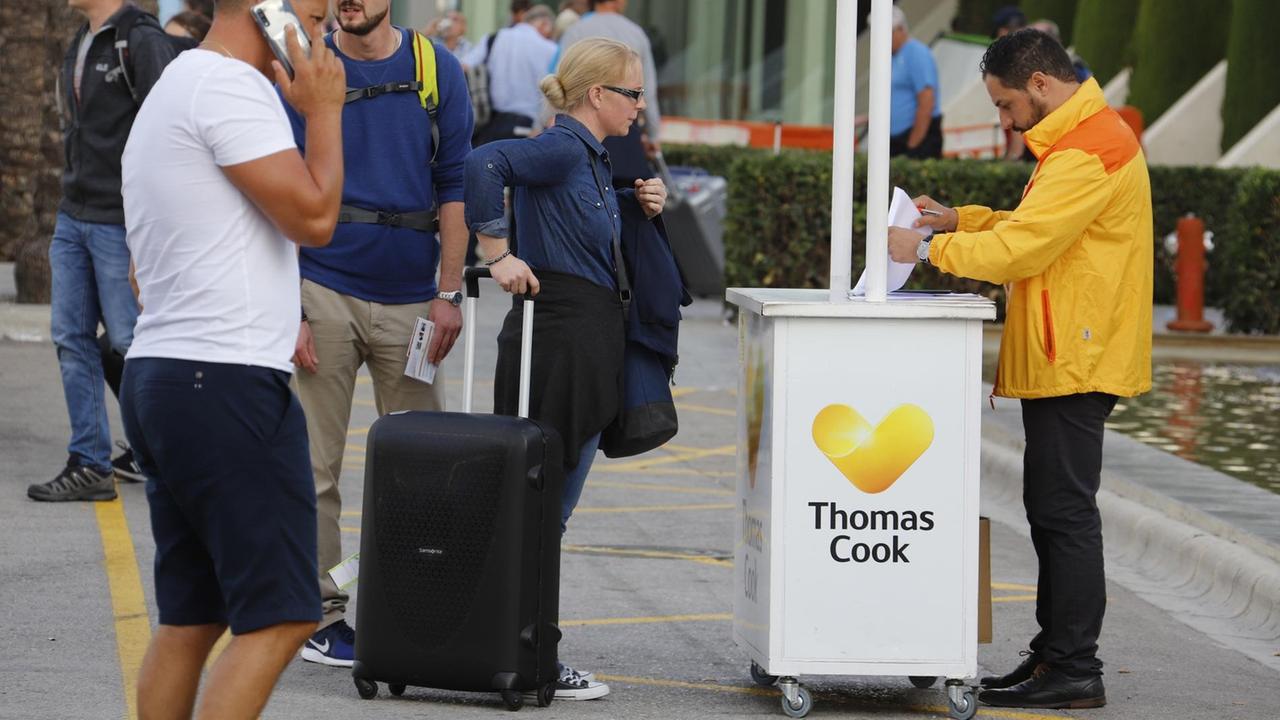 Passagiere stehen am Flughafen Palma de Mallorca am Tag des Scheiterns von Thomas Cook an einem Informationsschalter.
