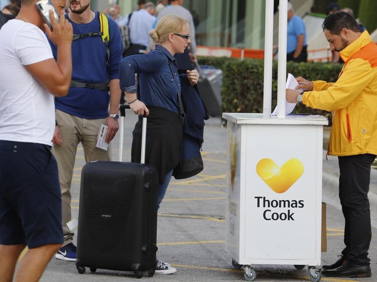 Passagiere stehen am Flughafen Palma de Mallorca am Tag des Scheiterns von Thomas Cook an einem Informationsschalter.