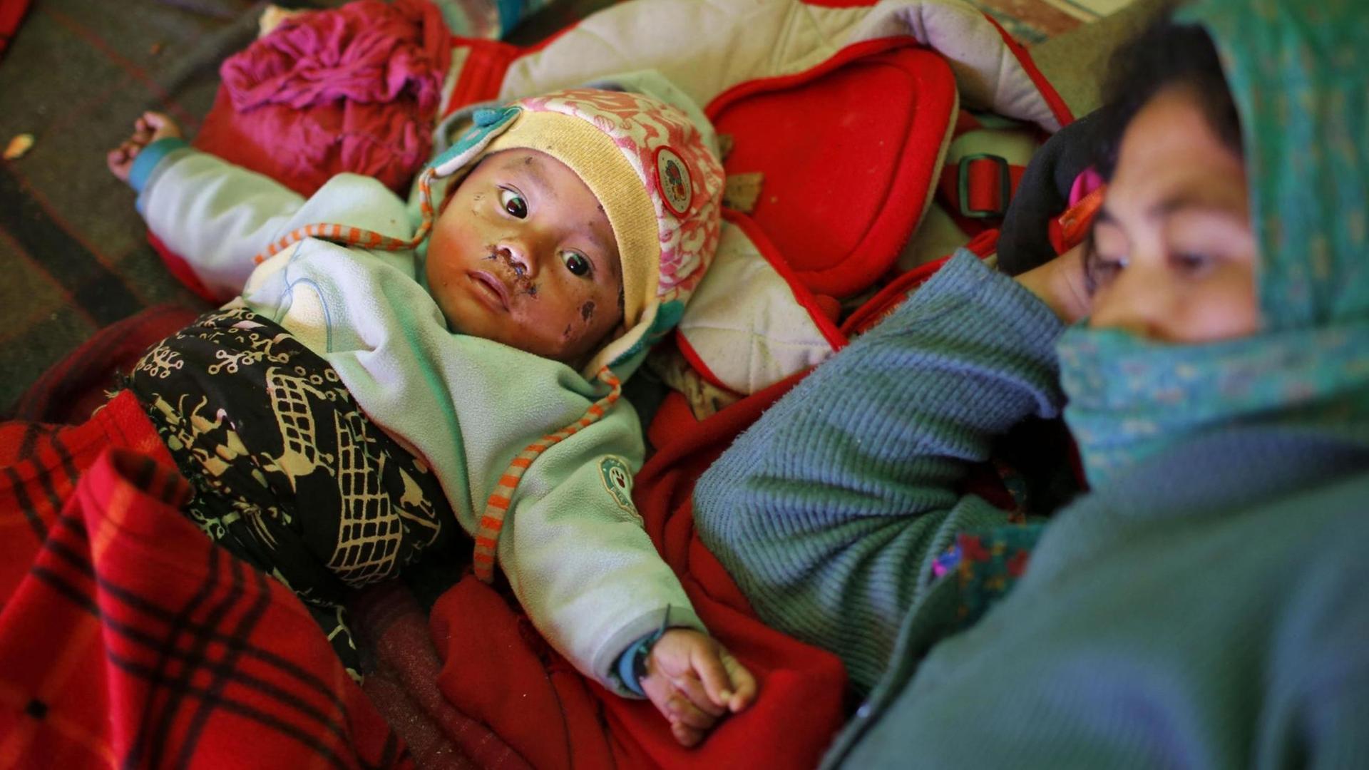 Eine nepalesische Mutter liegt mit ihrem Kind in einem Notzelt.