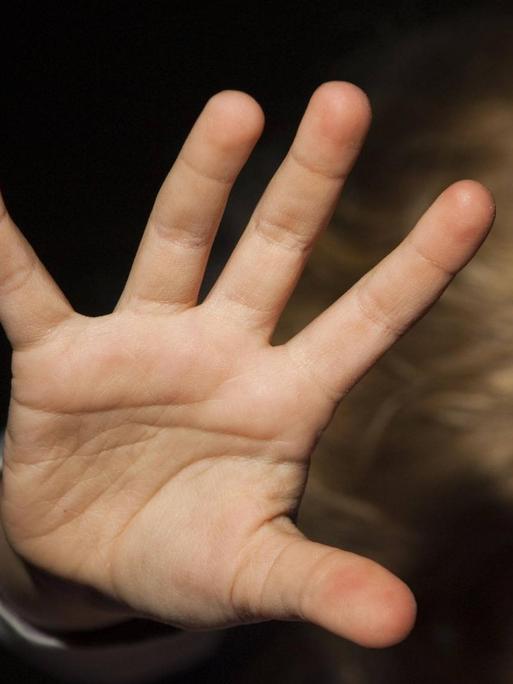 Ein Kind streckt die Hand zur Abwehr nach oben.