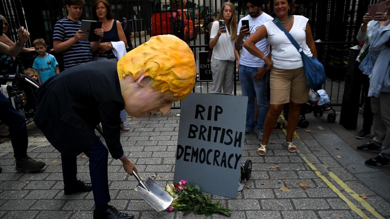 Das Foto zeigt Proteste gegen die Politik des britischen Premierministers Boris Johnson. Ein Demontrant trägt dabei einen Pappmache-Kopf, der Johnson darstellen soll.