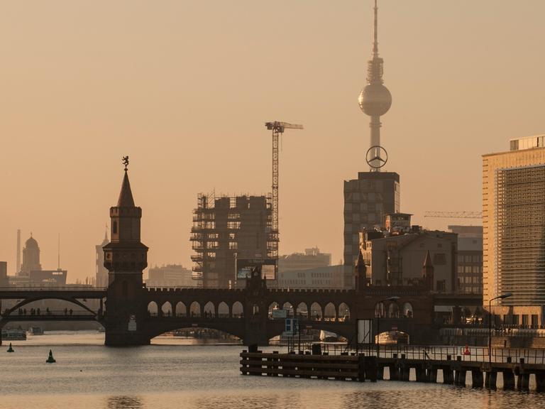 Die Skyline hebt sich in Berlin im Licht der untergehenden Sonne ab. Im Vordergrund die Oberbaumbrücke, dahinter der Fernsehturm.