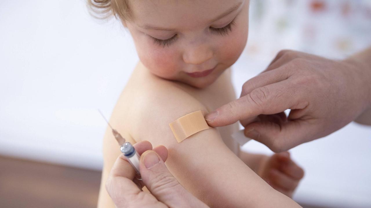 Ein Kleinkind bekommt nach einer Impfung ein Pflaster auf die Einstichstelle geklebt.