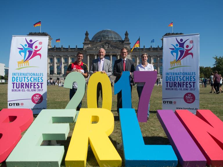 Zu sehen:  Lukas Dauser (l-r), Präsident des Deutschen Turner-Bundes (DTB), Rainer Brechtken, der Regierende Bürgermeister von Berlin, Michael Müller (SPD) und die Helferin Monika Richter auf der Wiese vor dem Reichstag