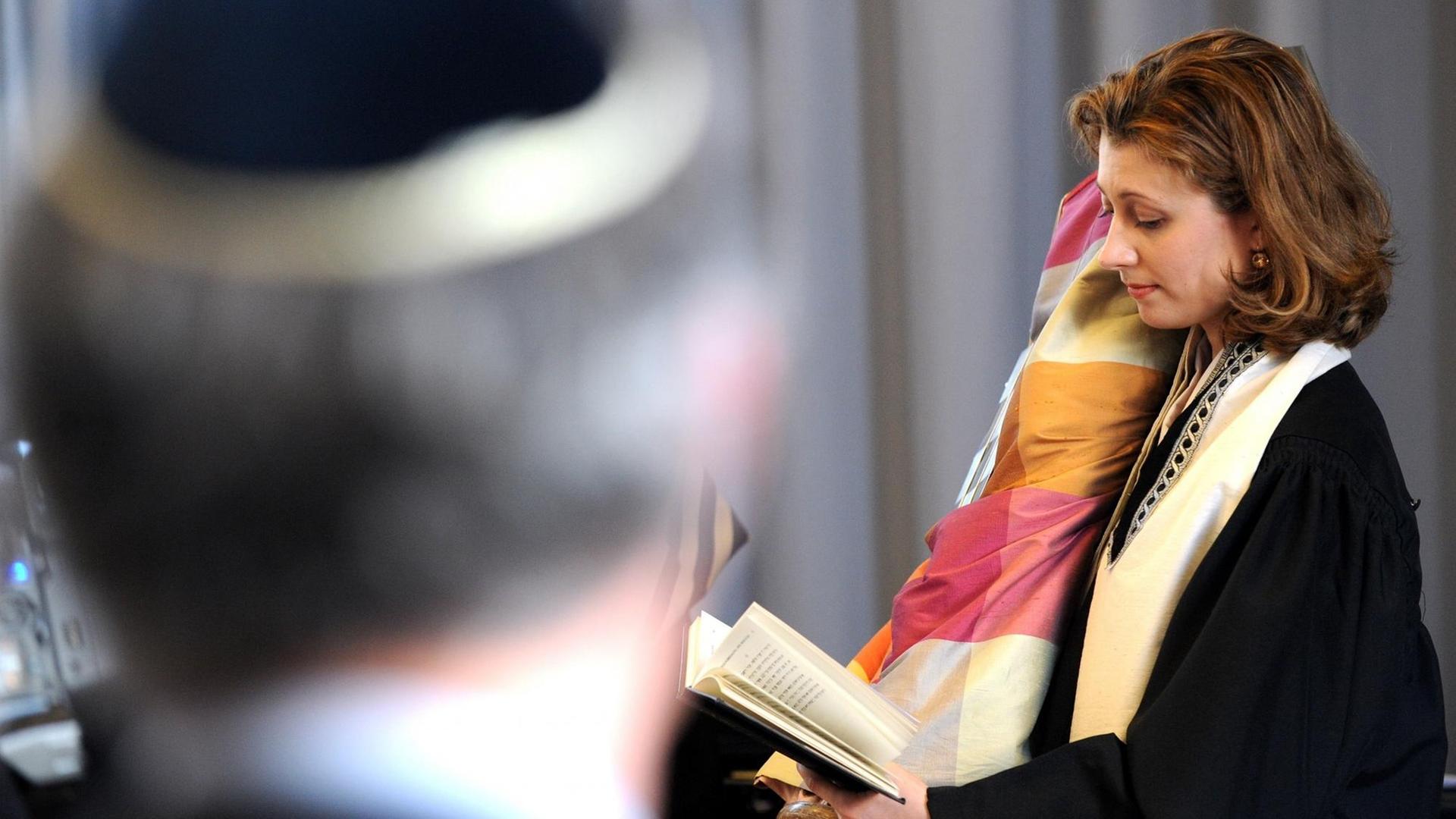 Die Rabbinerin in Oldenburg, Alina Treiger, hält am Sonntag (27.03.2011) zu ihrer offiziellen Amtseinführung im Kulturzentrum PFL in Oldenburg die Tora-Rolle im Arm und liest ein Gebet vor.