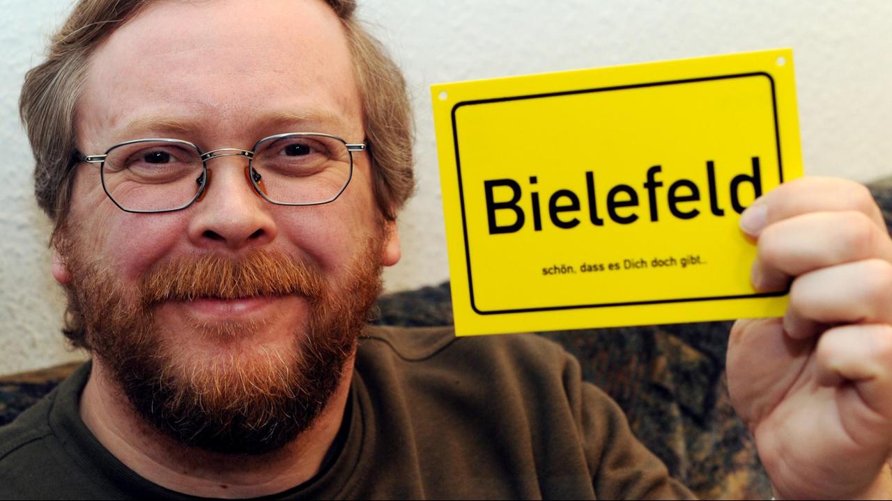 Achim Held, Erfinder der Bielefeld-Verschwörung zeigt am 05. Mai 2013 in Kiel ein Schild mit der Aufschrift "Bielefeld - schön dass es dich doch gibt".