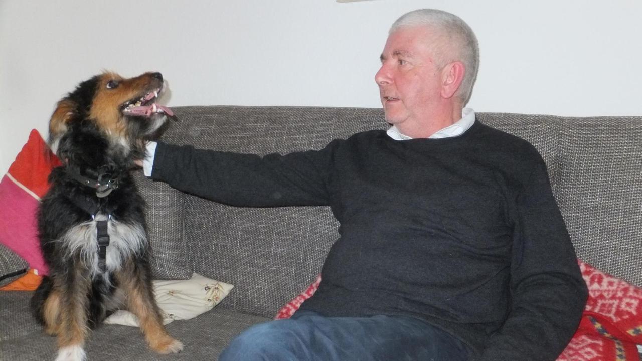 Erwin Grosche sitz mit seinem sein Hund Milik am Sofa