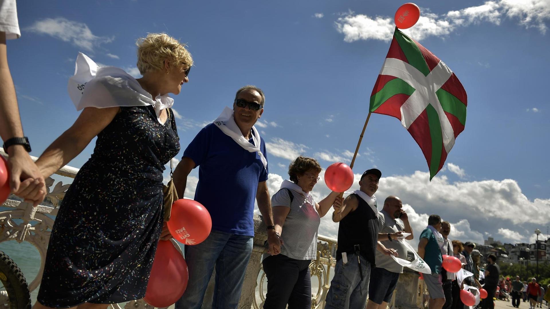 Spanien, San Sebastian: Ein Mann hält eine baskische Flagge, während er mit tausenden anderen Demonstranten am Strand von La Concha eine Menschenkette bildet und für die Unabhängigkeit des Baskenlandes demonstriert.