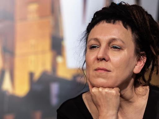 Olga Tokarczuk sitzt auf einem Podium und hört den Fragen zu. Olga Tokarczuk sitzt auf einem Podium und hört den Fragen zu.