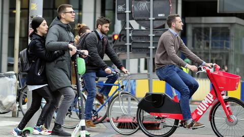 In Brüssel fährt ein Mann auf einem E-Tretroller über eine Straße.