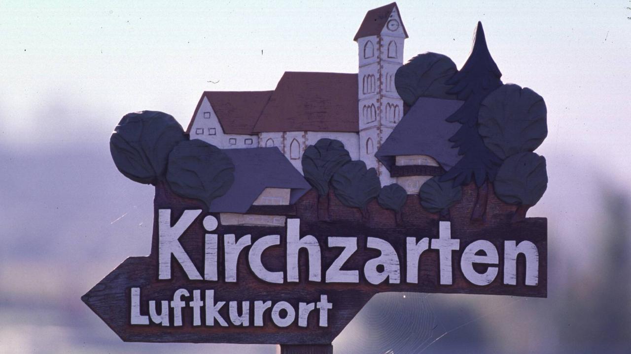 Auf dem Wegweiser zum Luftkurort Kirchzarten sind barocke Gebäude und grüne Bäume zu sehen. Auf dem Wegweiser zum Luftkurort Kirchzarten sind barocke Gebäude und grüne Bäume zu sehen.