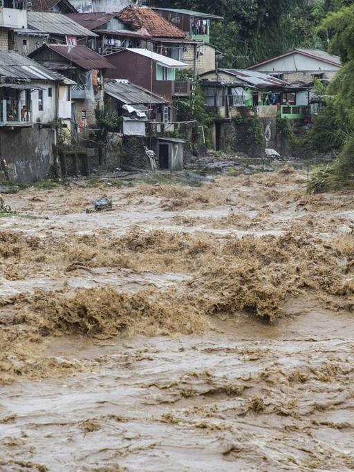 Wassermassen des Ciliwung schießen durch die Kampongs - alte, dörflich anmutende Viertel, in denen die Einwohner bis heute auf traditionelle Weise leben. Bogor, West Java, Ciliwung River. Februar 2018.