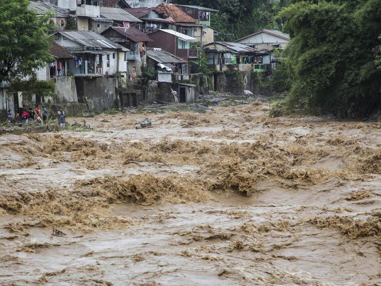 Wassermassen des Ciliwung schießen durch die Kampongs - alte, dörflich anmutende Viertel, in denen die Einwohner bis heute auf traditionelle Weise leben. Bogor, West Java, Ciliwung River. Februar 2018.