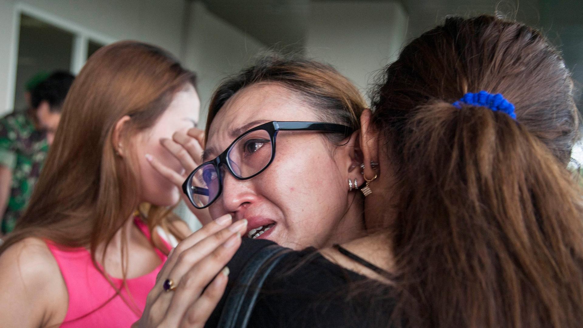 Zwei indonesische Frauen umarmen sich weinend.