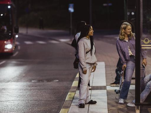 Freundinnen stehen in der Nacht an einer Bushaltestelle auf dem Nachhauseweg. (Symbolbild)