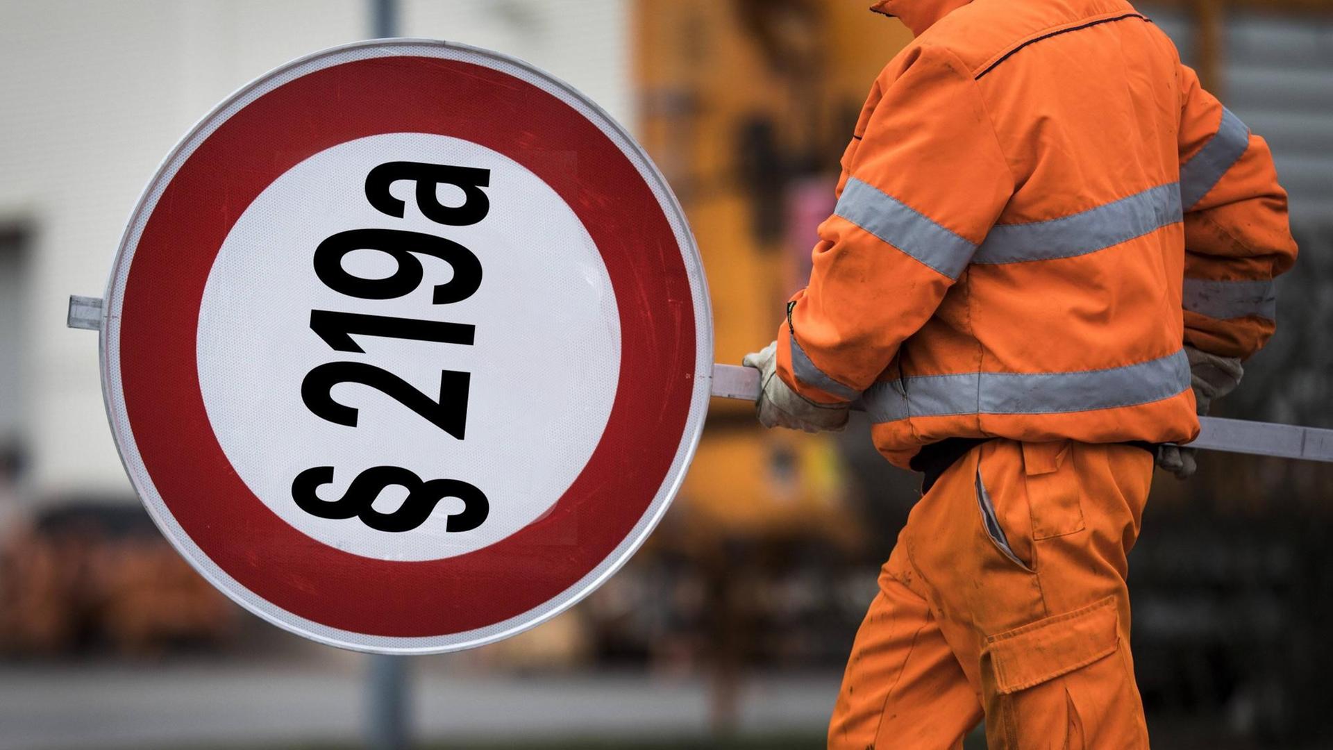 Ein Mitarbeiter der Autobahnmeisterei mit einem Schild auf den "§ 219a" montiert ist.