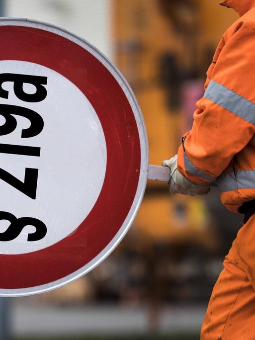 Ein Mitarbeiter der Autobahnmeisterei mit einem Schild auf den "§ 219a" montiert ist.