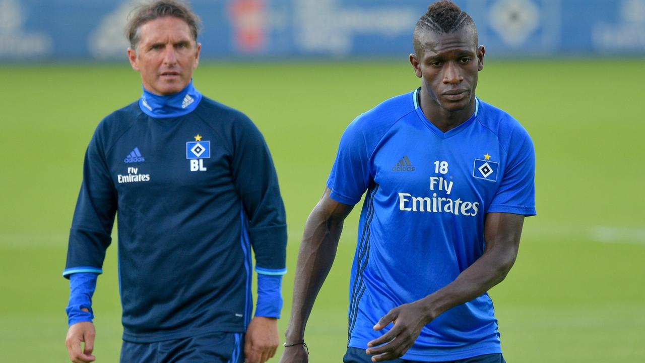 Der Flüchtling Bakery Jatta (r.), der einen Profivertrag beim HSV unterschrieben hat, wird von Hamburgs Trainer Bruno Labbadia beim Training beobachtet.