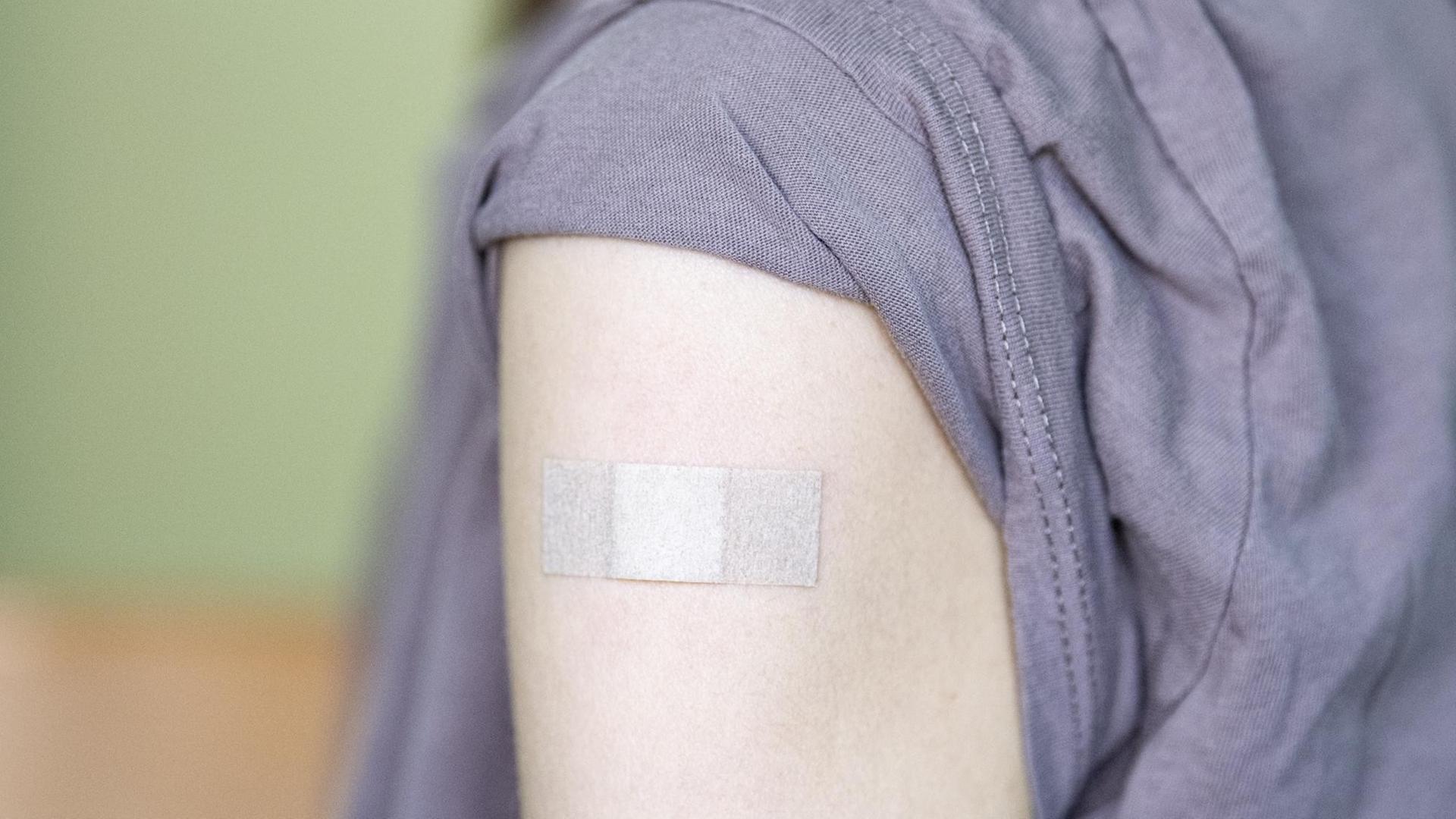 Auf dem Arm eines Jugendlichen klebt ein Pflaster, nachdem er bei einem Kinder- und Jugendarzt geimpft wurde.