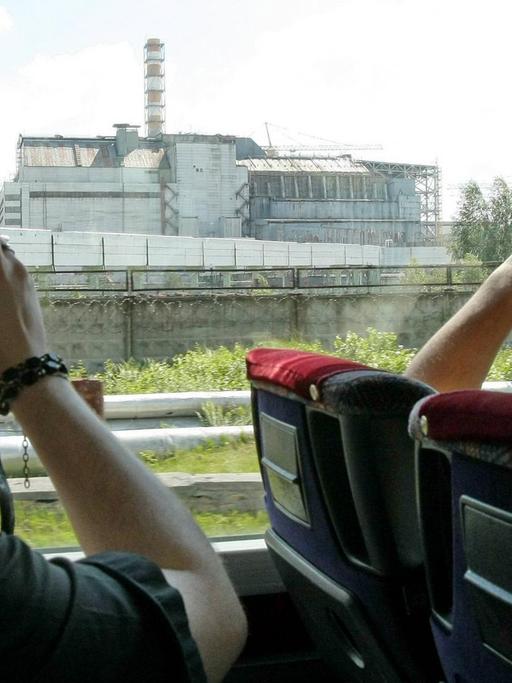 Touristen fahren in einem Bus an dem Atomreaktor von Tschernobyl vorbei und machen Fotos.