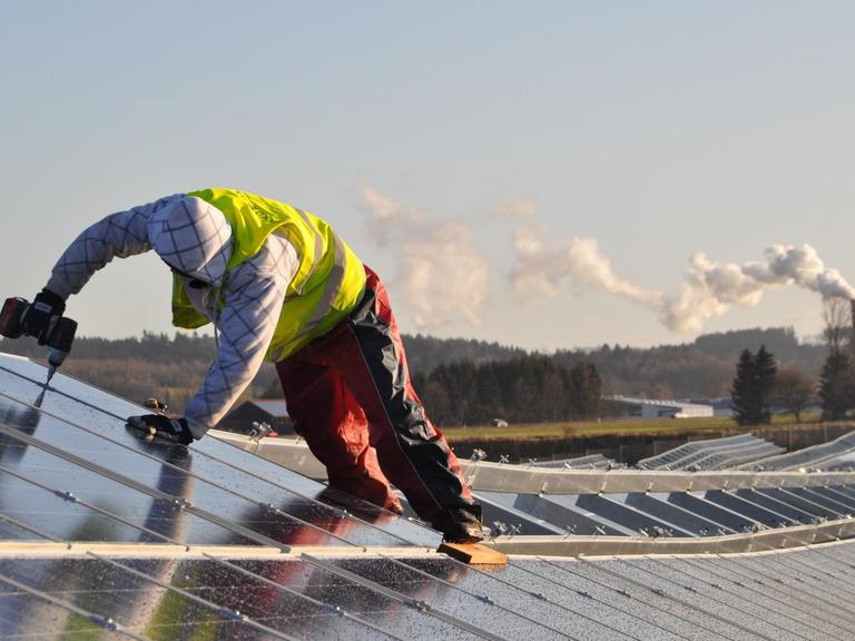 Ein Arbeiter verschraubt Sonnenkollektoren im Solarpark in Leutkirch (Kreis Ravensburg).