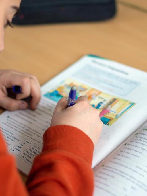Ein Schüler schreibt während des Unterrichts in einer Grundschule in einem Schulbuch.
