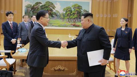 Der nordkoreanische Machthaber Kim Jong Un gibt einem Entsandten aus Südkorea die Hand. Im Hintergrund stehen weitere Personen.
