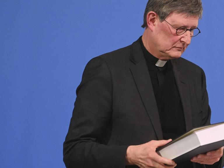 Kardinal Rainer Maria Woelki hält das Gutachten kurz nach der Veröffentlichung in der Hand.