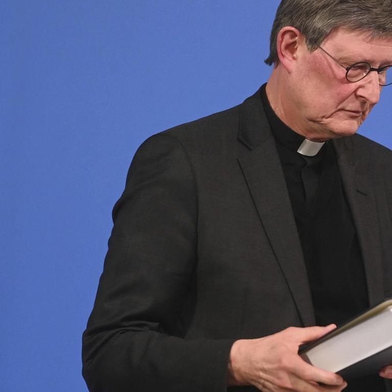 Kardinal Rainer Maria Woelki hält das Gutachten kurz nach der Veröffentlichung in der Hand.