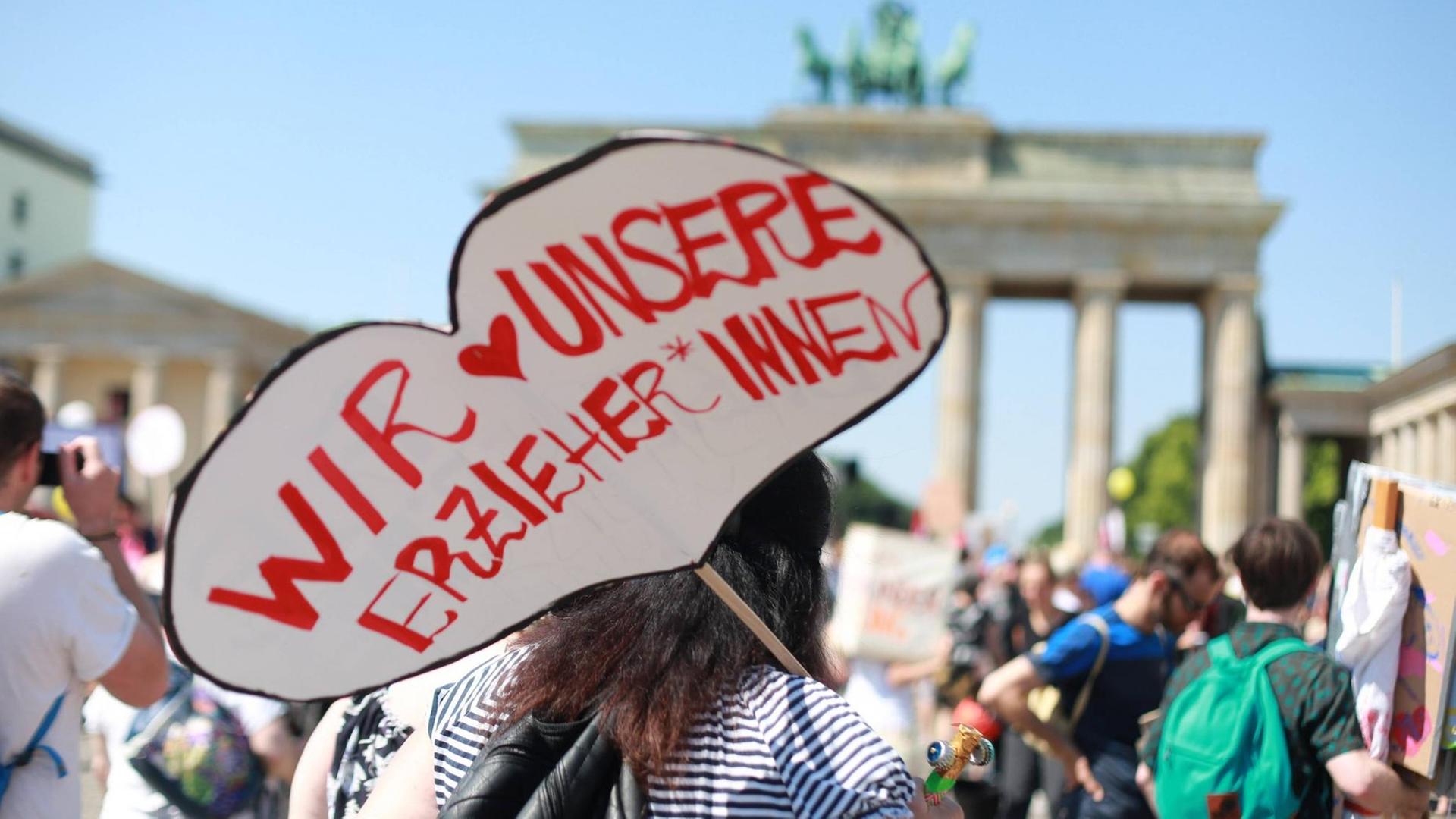 "Wir lieben unsere Erzieher" steht auf dem Plakat einer Demonstrantin vor dem Brandenburger Tor in Berlin
