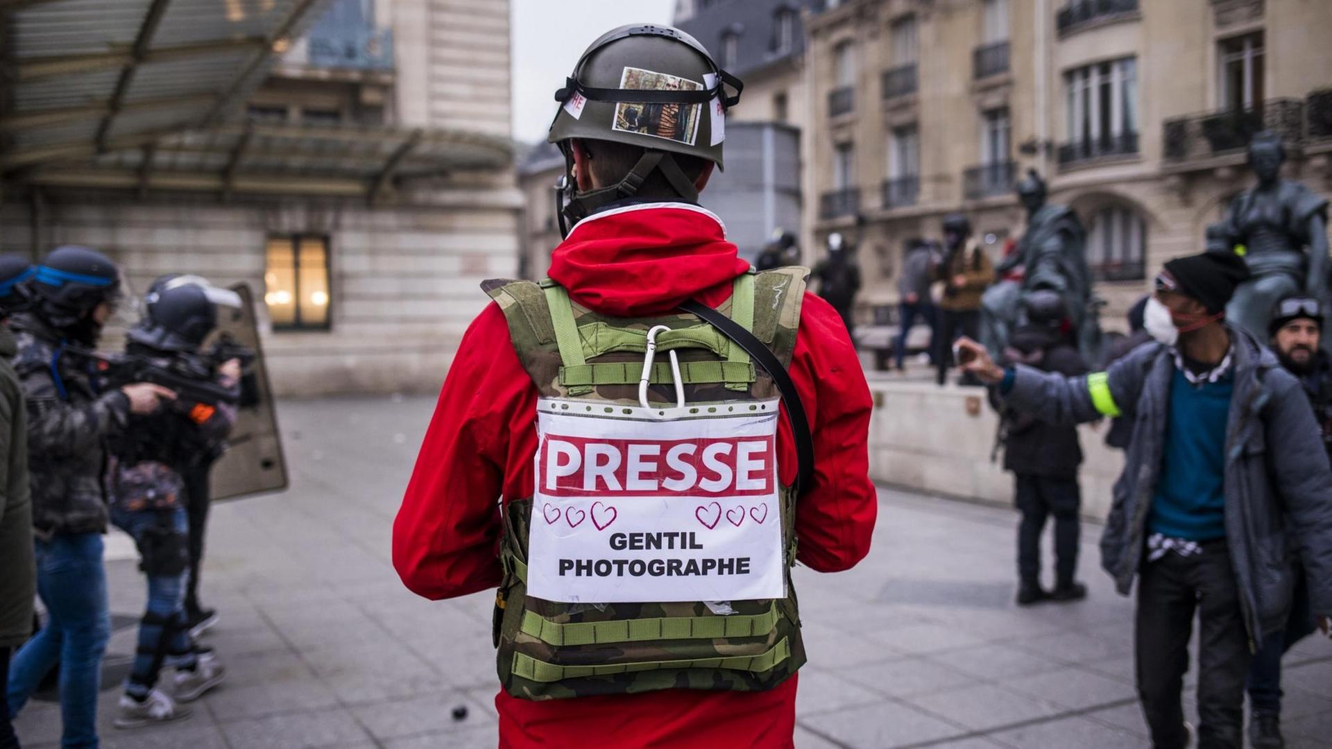 Ein Journalist in Paris trägt bei den Gelbwesten-Protesten ein Schild mit der Nachricht "Presse - freundlicher Fotograf" auf dem Rücken.