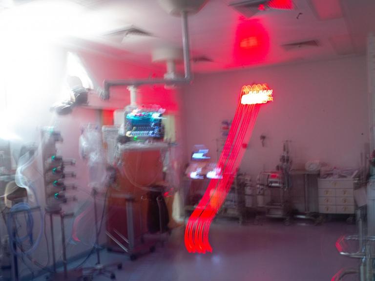 Filmszene aus der Dokumentation "Charité intensiv". Das Foto in verschischter Ästhetik ein Behandlungszimmer auf der Intensivstation.