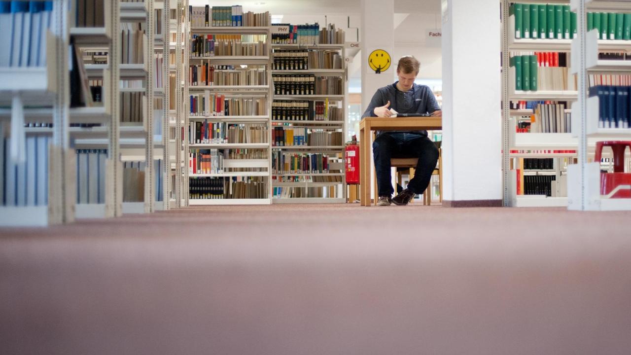 Ein Student sitzt am 07.11.2012 in der Bibliothek der Universität Hildesheim an einem Schreibtisch und liest.