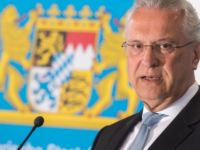 Der bayerische Innenminister Joachim Herrmann, CSU, spricht vor einem Landeswappen