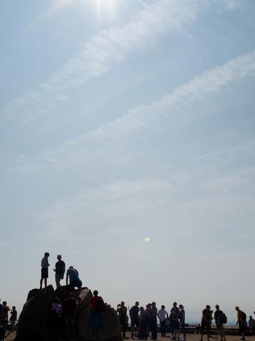 Besucher auf dem Brocken-Gipfel bei tiefstehender Sonne über dem Gipfel-Plateau des Berges