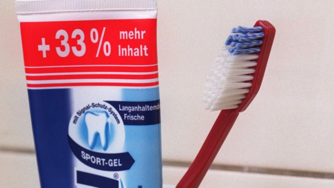Zahnpastatube mit Zahnbürste in einem Becher.