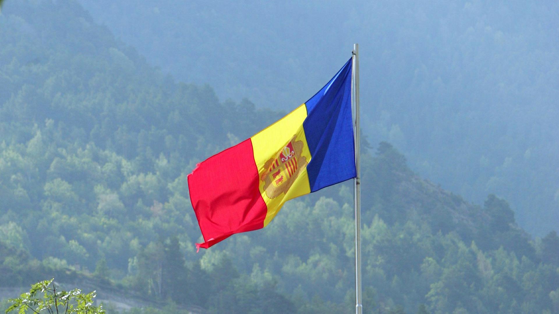 Die Nationalflagge von Andorra, im Hintergrund sind die Pyrenäen zu erkennen.