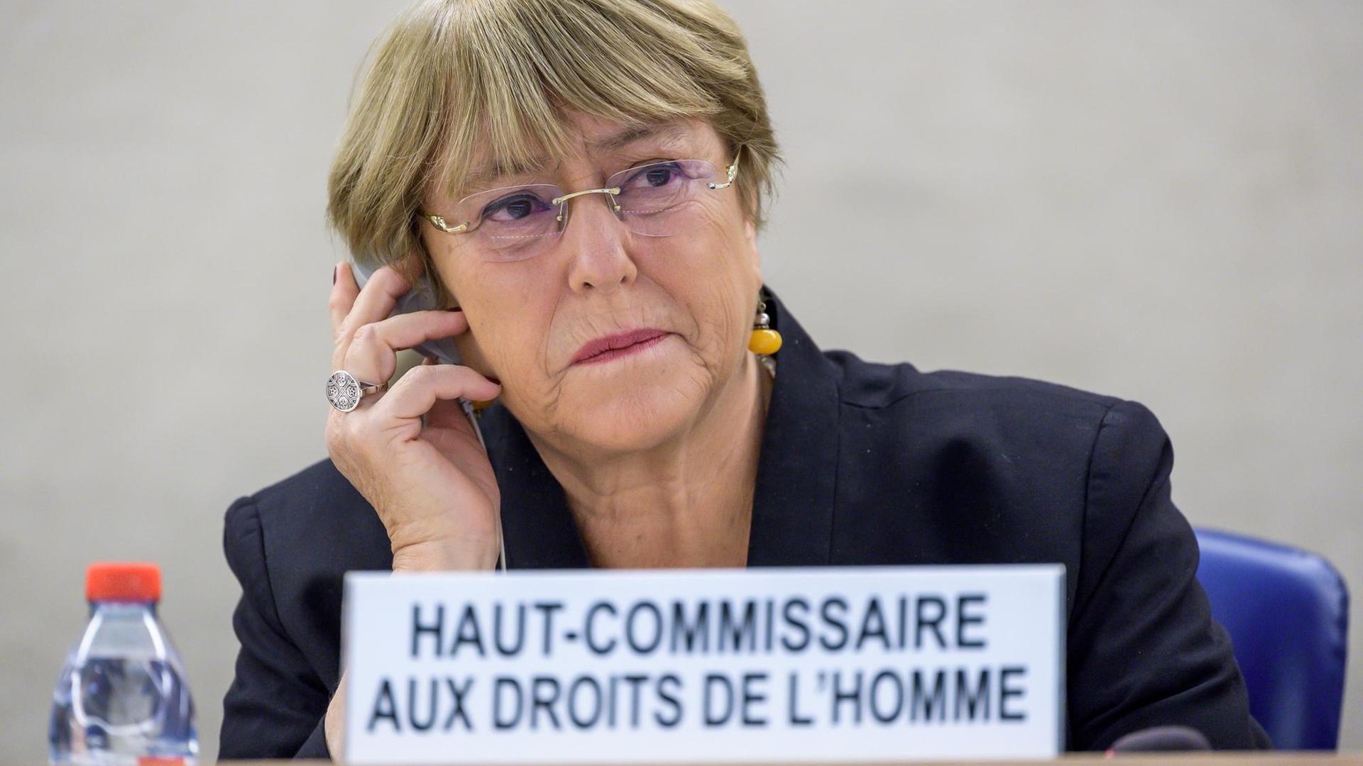 Michelle Bachelet sitzt an einem Schreibtisch und telefoniert mit einem Handy.
