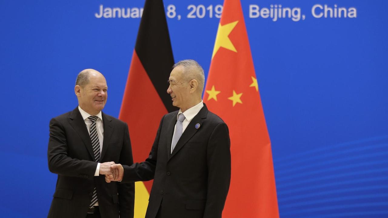 Der deutsche Finanzminister Olaf Scholz gibt dem chinesischen Vize-Premierminister Liu He vor den deutschen und chinesischen Flaggen die Hand.