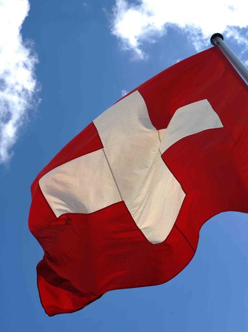 Die Fahne der Schweiz weht vor blauem Himmel