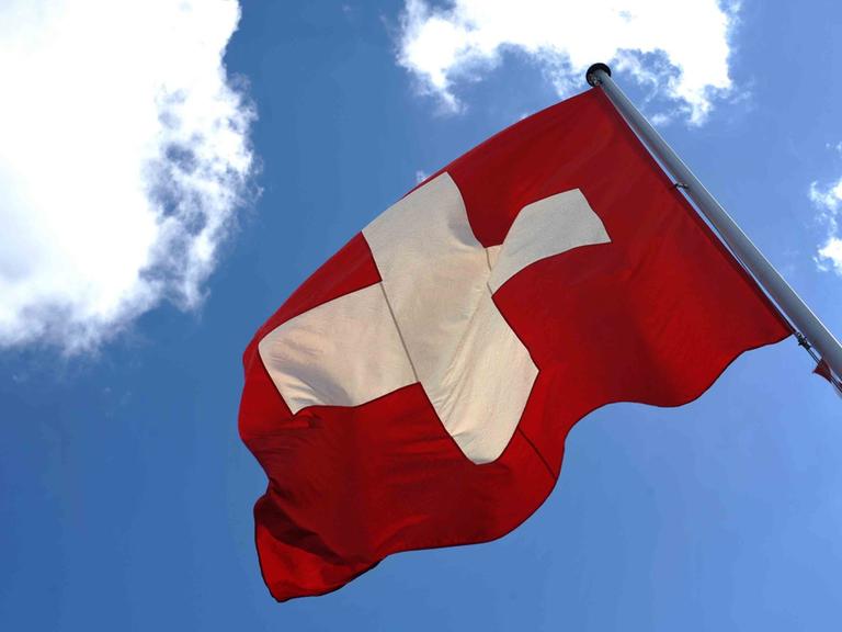 Die Fahne der Schweiz weht vor blauem Himmel