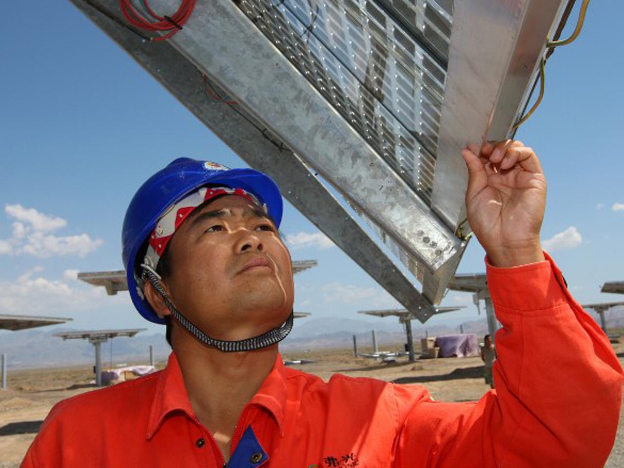 Ein Arbeiter prüft ein Solarpanel auf einem Feld im chinesischen Hami.